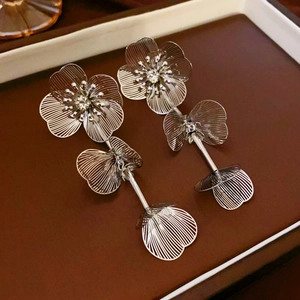 Vue détaillée de boucles d'oreilles fleurs argentées avec pompons et strass sur cuir