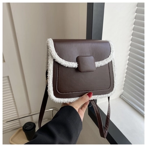 Detail of a brown square crossbody bag with white faux fur trim and sleek metal buckle