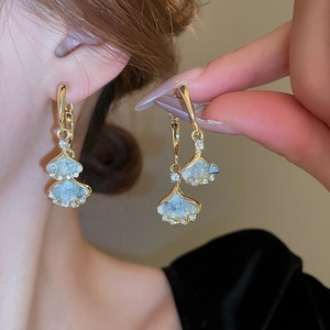 Macro view of gold fan-shaped earring with crystals and blue mother of pearl inlay