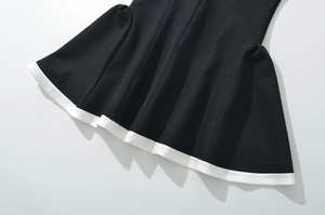 Detail of a black dress hem with elegant white trim contrast and pleated fabric texture
