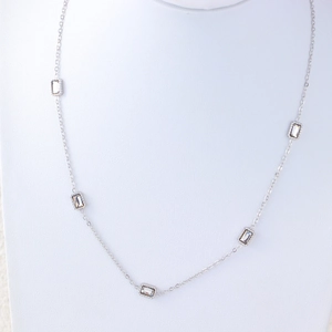Detail of silver titanium steel necklace featuring five rectangular clear zircon charms on neck model