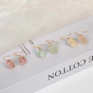 Three pairs of natural raw crystal earrings with gold wire wrap hooks on white silk fabric