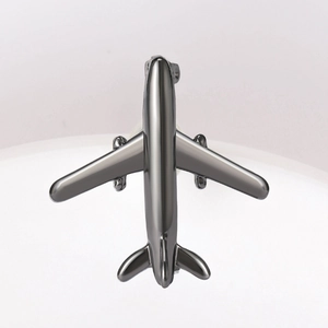 Top view of a minimalist silver airplane brooch with a smooth polished metal surface