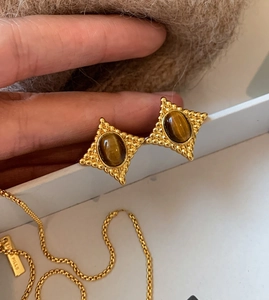 Détail des boucles d'oreilles en œil de tigre rétro et collier doré à pendentif
