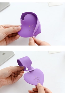 Detail of purple heart-shaped faux leather luggage tag with embossed texture and strap