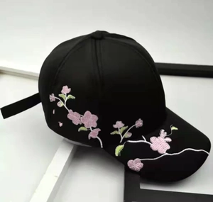 Close-up of pink flower embroidery on a black baseball cap with curved brim detail