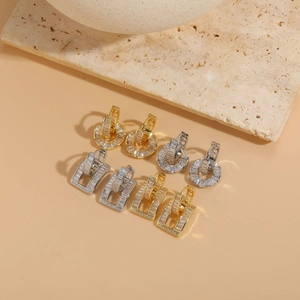 Detail of cross-over hoop earrings with zircon stones in gold and silver plating