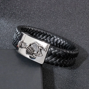 Macro detail of men's leather braided bracelet featuring a silver skull magnetic clasp