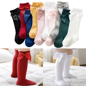 Detailed knit texture and large bow accents on multi-color knee-high baby socks