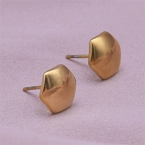 Macro shot of matte gold irregular pentagon stud earrings with brushed metal texture