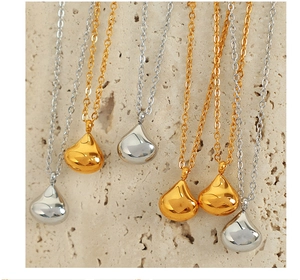 Close-up of elegant gold and silver teardrop pendant necklaces on natural rock