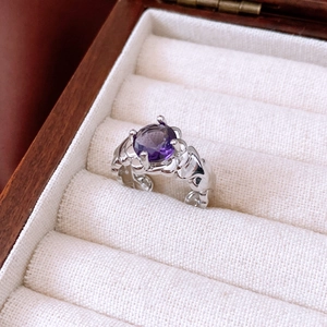 Macro detail of silver ripple ring with a large purple zircon in a white jewelry box