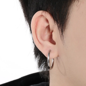 Polished silver stainless steel round hoop earring worn on female model's ear