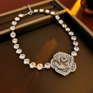 Détails macro d'un collier à pendentif floral argenté avec pompon en cristal et micro-pavé