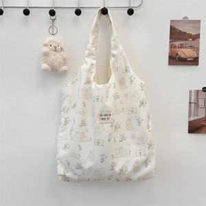 Détail de motifs lapins et fleurs sur sac cabas en toile crème avec écusson décoratif