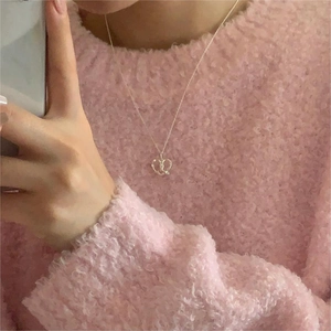 Detailed view of simple silver heart pendant necklace styled on pink sweater