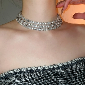 Detailed view of elegant triple-layer necklace featuring white pearls and shiny rhinestones