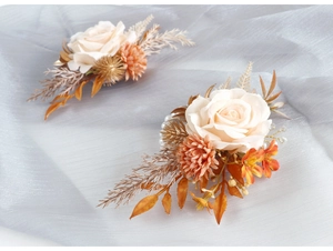 Détail d'un corsage de poignet rose crème avec œillets orange et feuilles dorées de mariage