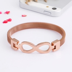 Close-up of rose gold infinity charm bracelet with mesh strap on a white surface