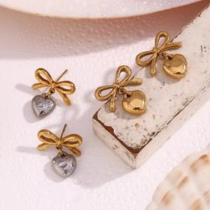 Gros plan de boucles d'oreilles nœud et cœur plaquées or 18 carats avec texture goutte d'eau