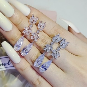 Detail showing rose gold and silver pear-shaped zircon earrings held by hand