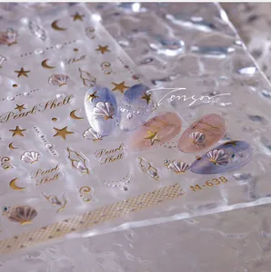 Macro shot of M-638 gold embossed seashell and star nail art stickers on gradient base