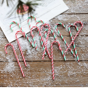 Red, green and white candy cane ornaments on rustic wood surface with fake snow