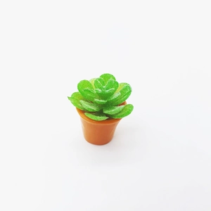 Miniature dollhouse succulent plant in orange pot with green flocked leaves on white background