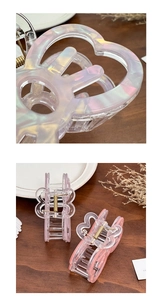Macro detail of iridescent butterfly hair claw clip with pink gradient on wooden surface