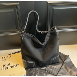 Detail of suede and leather stitching on black hobo tote bag with adjustable strap