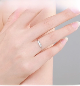 Close-up of minimalist S925 sterling silver ring with three tiny heart-shaped zircon stones