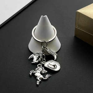Close-up of silver cowboy keychain featuring horse, hat, and boot charms on a white stand