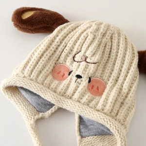 Close-up of cream knit kid's hat featuring puppy ear details and soft inner lining