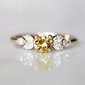 Macro shot of an elegant gold ring featuring a yellow center stone and leaf-like side gems