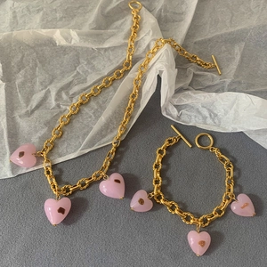 Detail of pink Murano glass heart charms on a gold-plated necklace and bracelet set