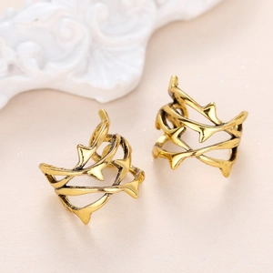 Dettaglio di ear cuff dorati vintage a forma di rami di spine con finitura in metallo