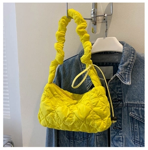 Detail der gelben gesteppten Halbmondtasche mit gerafftem Griff an einer Jeansjacke