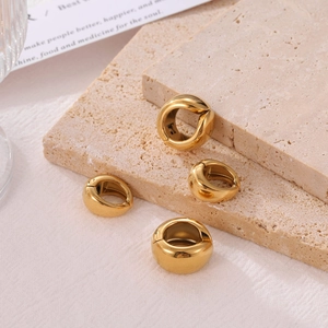 Minimalist thick gold C-shaped clip-on hoop earrings on textured stone background