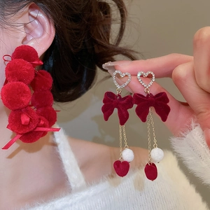 Detail of red flocked bow earrings with rhinestone hearts and long chain tassels