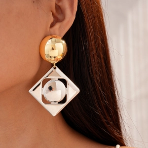 Close-up of geometric gold and silver mixed metal earrings worn on a model's ear