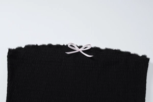 Gros plan sur le tissu plissé noir avec un nœud en satin rose et bords volantés