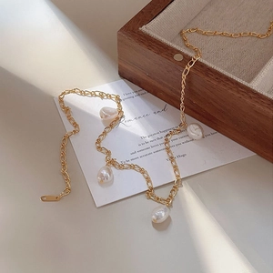 Elegant gold paperclip chain necklace with irregular baroque pearls on a vintage card
