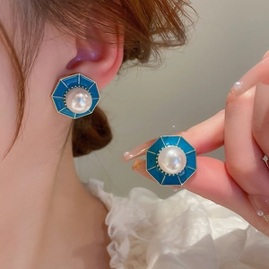 Close-up of vintage octagonal teal enamel earrings with central imitation pearl inlay