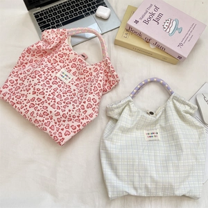 Vue détaillée de sacs cabas en toile fleurie avec poignées tressées et étiquettes de marque