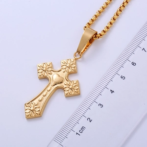 Detailed view of golden gothic cross pendant with heart engraving next to a metric ruler