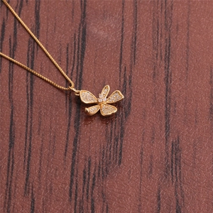 Detail of a sparkling gold butterfly necklace with cubic zirconia on wood background