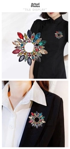 Détail d'une broche couronne en cristal vintage avec strass colorés sur un vêtement