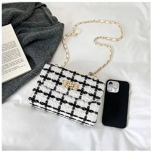 Close-up of black and white tweed chain bag with gold buckle next to a smartphone