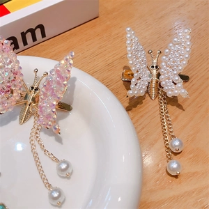 Detail of butterfly hair clips with pink rhinestones and pearl tassels on a ceramic tray