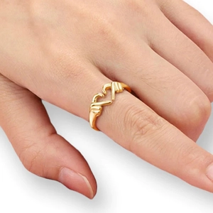 Primer plano de un anillo dorado con dos manos formando un corazón en un dedo